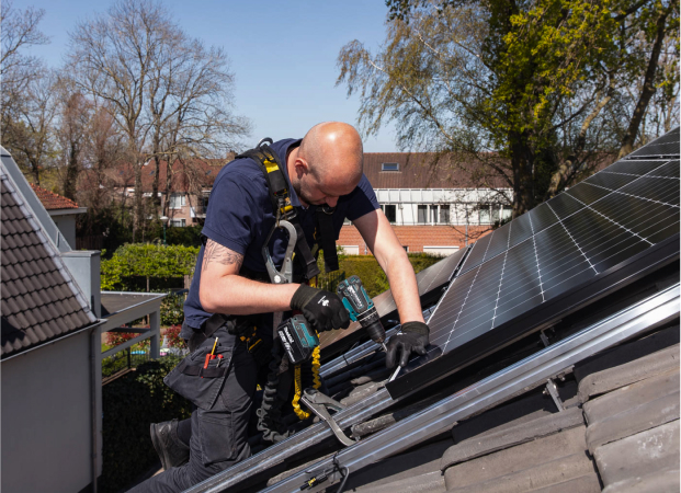 Installateur die de zonnepanelen aan het plaatsen is op een dak.